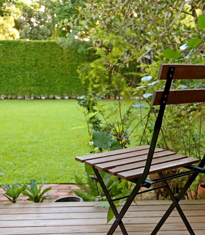 Terrasse en bois aménagée avec une chaise face à un jardin entretenu