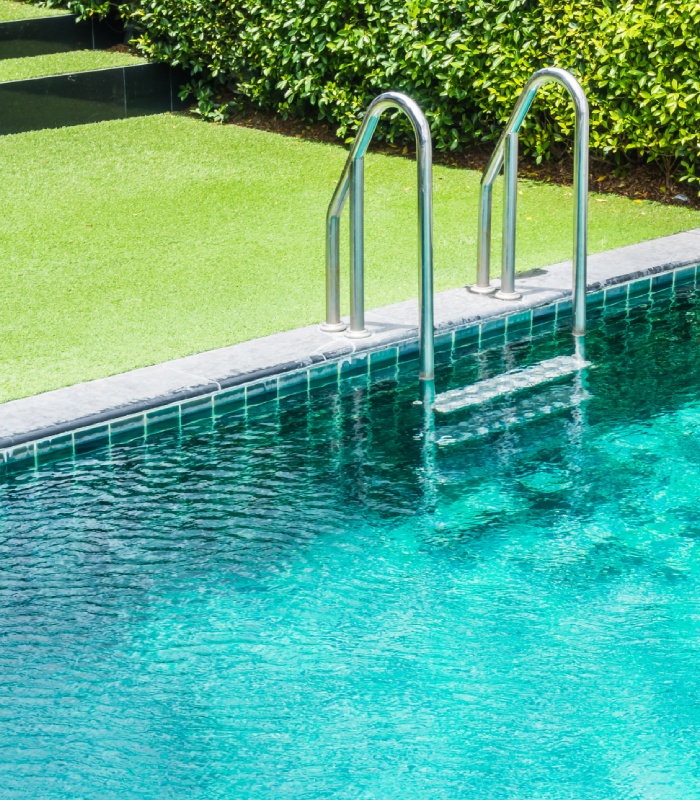 Piscine extérieure entourée de gazon et de haies dans un jardin paysager